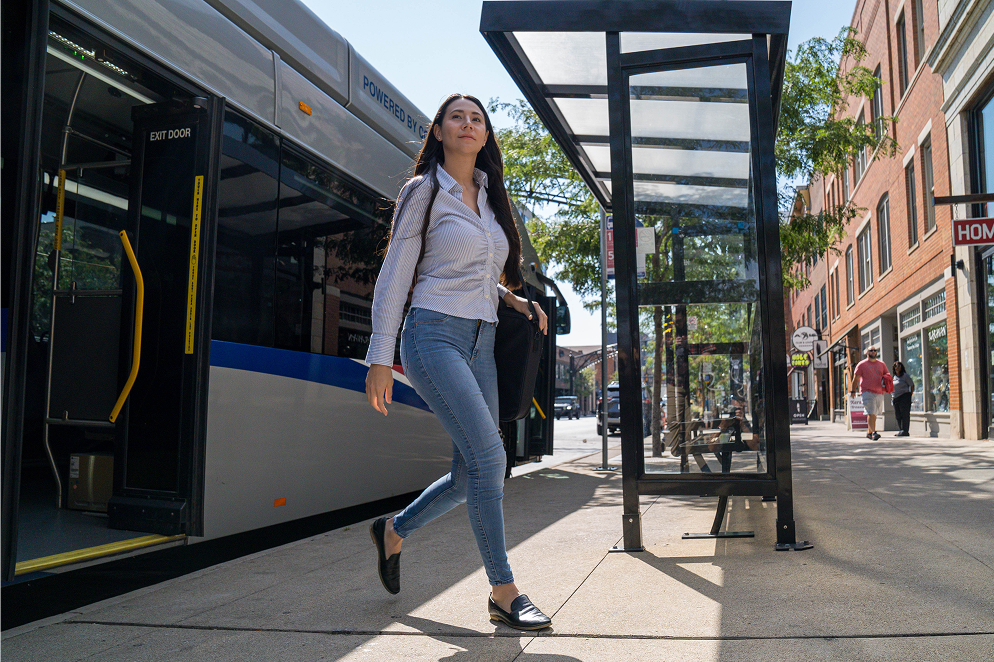 A rider walking from a COTA bus at a downtown transit stop